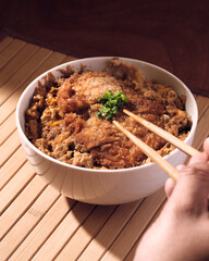 Person eating a bowl of japanese katsudon