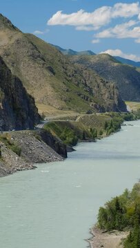 Vertical video of Altai natural landscape with river Katun under blue sky with clouds. On the left bank of the river there is Chuya Highway.