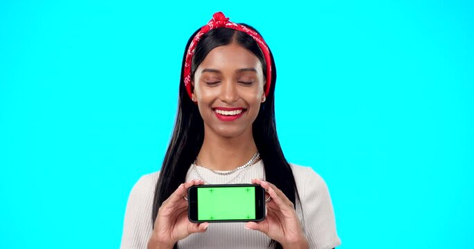 Green screen, face and phone by gen z woman in studio for advertising, space and on blue background. Smartphone, display and portrait of girl fashion influencer showing social media, blog or website