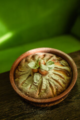 Apple pie with powdered sugar, berries of physalis and mint is on the table