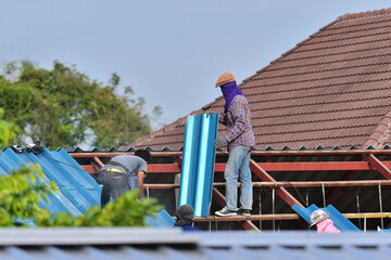 Blue carved roofings are roofed by the workers for home renovation