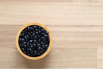 Top view of black beans in a bowl on wooder background, Healthy eating concept