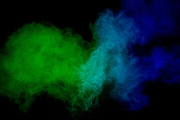 Green and blue powder explosion on black background.Freeze motion of green and blue dust cloud.
