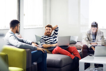 Businessmen discussing in creative office seen through glass