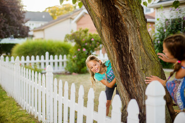 Happy sisters playing hide and seek in backyard
