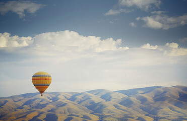 Hot air balloon flying over mountains in Cappadocia