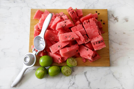 High angle view of chopped watermelon and lemons on cutting board with squeezer