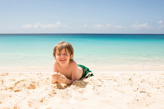 Smiling boy lying on sand at beach