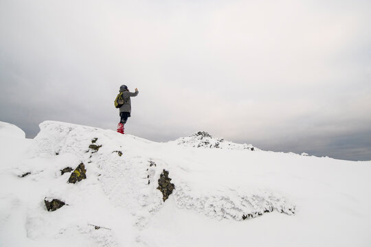 Low angle view of hiker standing on snow covered field against cloudy sky