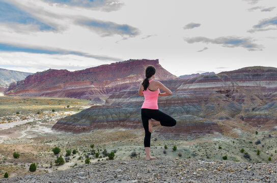 Rear view of woman standing in tree pose on rock formation