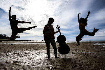 silhouetted dancers and cellist on Cape Cod beach