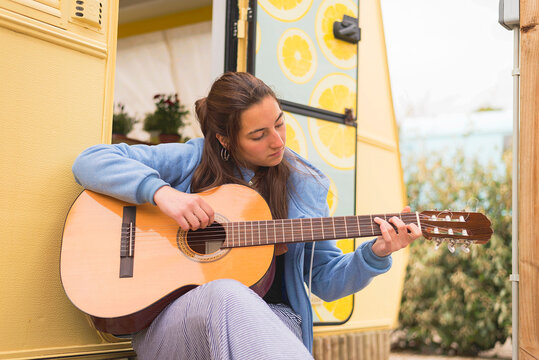 Young woman playing guitar at a campsite.