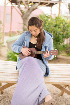 Young woman playing guitar at a campsite.