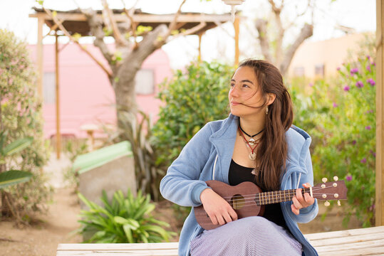 Young woman playing guitar at a campsite.