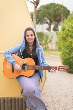Young woman playing guitar at a campsite.