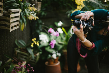 Woman photographs flowers in garden with DSLR camera