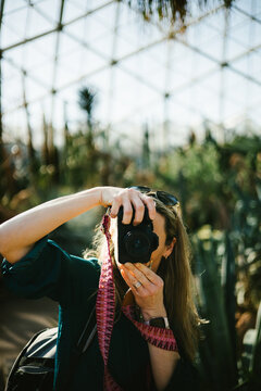 Woman takes photograph in botanical garden with dslr camera