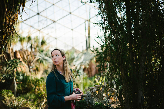Woman with camera in dome greenhouse with plants and sunshine