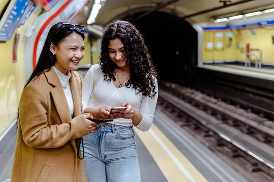 stock photo of two girls using the mobile in the subway