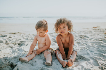Mixed race toddler boy twins sitting and playing in sad