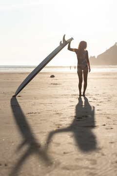 Woman standing with surfboard along the oregon coast