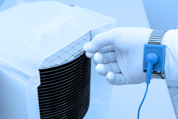 Gloved Hand Holding a Silicon Wafer in plastic holder box used in electronics for the fabrication of integrated circuits.Silicon wafer inspection.
