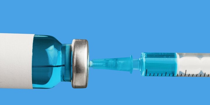 Closeup of a syringe with vial over blue background. Health and medicine concept.