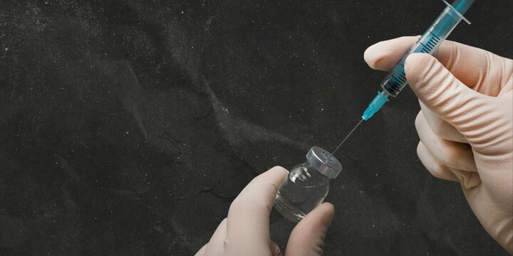 Closeup of a syringe with vial over dark background. Health and medical concept.
