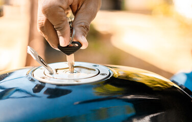 Hand opening the gas tank of the motorcycle, Motorcyclist opening the gas tank of the motorcycle....