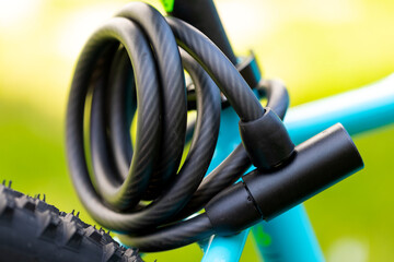 Picture of a black bicycle lock with a cable screwed on the metal frame of a sports bike