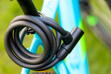 Picture of a black bicycle lock with a cable screwed on the metal frame of a sports bike