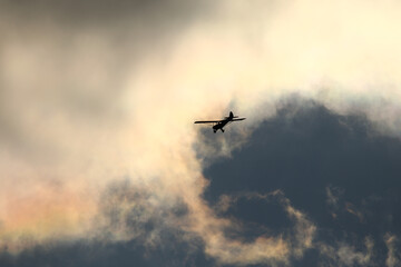 Small plane flying in the sky against dark clouds
