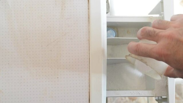 A Man Pours Washing Powder Into The Washing Machine Compartment, Top View