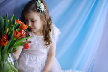 Beautiful girl in white dresses with a magnificent bouquet of the first tulips. International Women's Day. Girl with tulips.