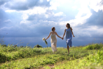 Fototapeta premium Young girls are walking in the field