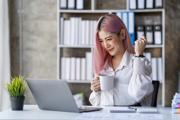 Portrait of an Asian businesswoman, a small business owner who successfully sells online and happily holds a smartphone with a laptop computer.