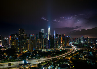 Aerial Panorama Kuala Lumpur cityscape during storm night with lightning strike above clouds