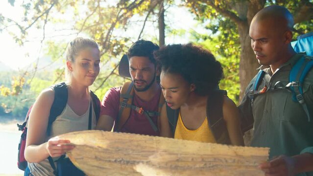 Group of friends on hiking vacation in countryside looking at map for directions  - shot in slow motion