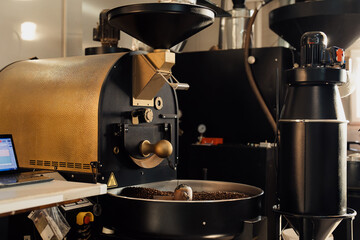 Professional machine in process of roasting and mixing coffee beans in modern industrial factory