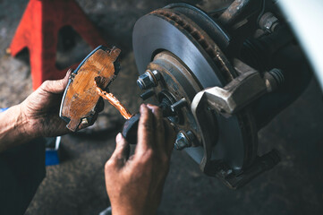 Auto mechanic applying a high temp brake grease on the brake pads.