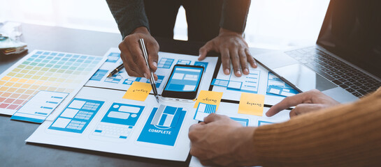 ux developers and ui designers, data researchers brainstorm on  tabletop mobile app interface wireframe design with client summary color codes the modern office Creative Digital Development Agency.
