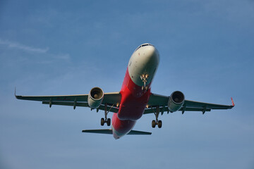 Airplane landing on blue sky background.