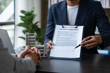 Entrepreneur, business owner, accountant, real estate agent A young Asian insurance agent explains the details of the condo purchase contract to calculate the financial risk for the client.