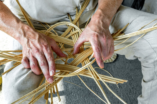 A male craftsman weaves a basket of willow branches. Folk Art Festival