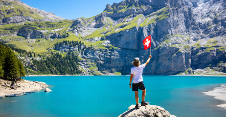children holding Switzerland flag- travel,  tourism on mountain lake oeschinensee