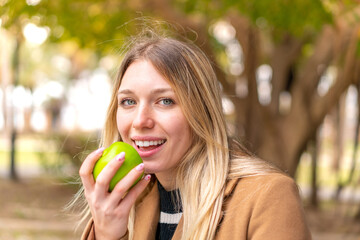 Young pretty blonde woman with an apple at outdoors