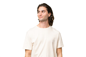 Young caucasian man isolated on green chroma background having doubts while looking side