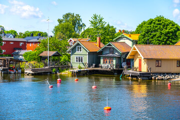 Small harbor with typical picturesque scandinavian wooden houses on a sunny day. Island of Vaxholm,...