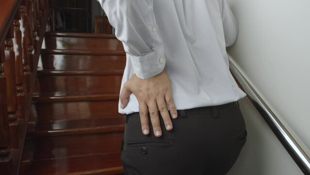 Man suffering from low back pain while walking up the stairs, have a backache, Office Syndrome health problems.
