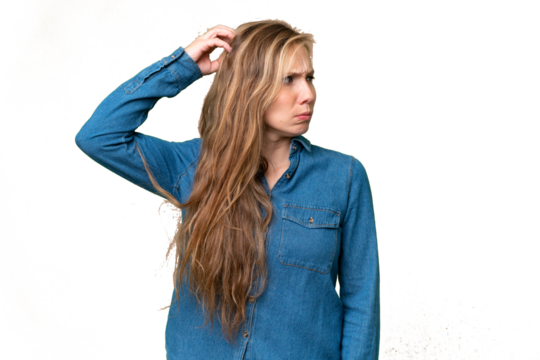 Young blonde woman over isolated background having doubts while scratching head